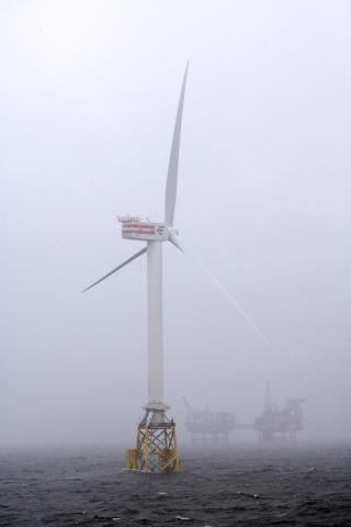 An offshore wind turbine and a large platform in the background